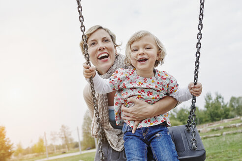 Mutter mit Tochter auf Schaukel auf Spielplatz - RORF00850