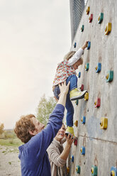Mädchen klettert mit Unterstützung der Eltern an einer Wand - RORF00854