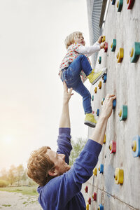 Mädchen klettert mit Unterstützung des Vaters auf eine Mauer - RORF00855