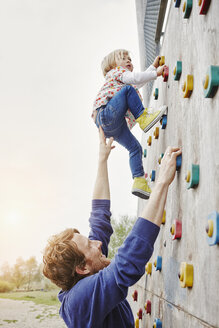 Girl climbing on a wall supported by father - RORF00855