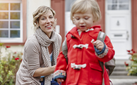 Mother looking after daughter leaving house stock photo