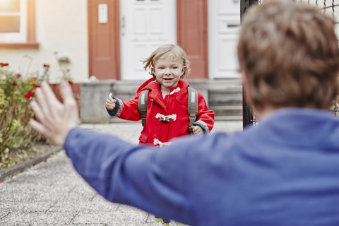 Happy daughter approacing father at house entrance stock photo