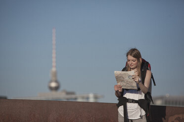 Deutschland, Berlin, Junge Frau mit Rucksack schaut auf Karte - MVCF00171