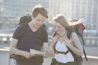 Germany, Berlin, Young couple traveling Berlin with backpacks, looking at map - MVCF00173