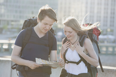 Germany, Berlin, Young couple traveling Berlin with backpacks, looking at map - MVCF00173