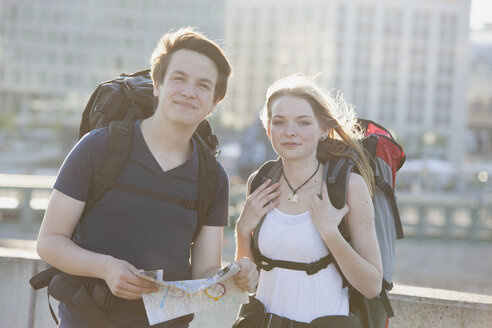 Germany, Berlin, Young couple traveling Berlin with backpacks, looking at map - MVCF00174