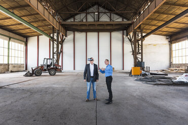 Zwei Geschäftsleute mit VR-Brille unterhalten sich in einer alten Industriehalle - DIGF02414