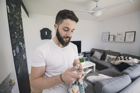 Young man using his smartphone at home stock photo