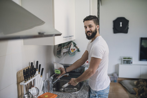 Junger Mann beim Geschirrspülen, lizenzfreies Stockfoto