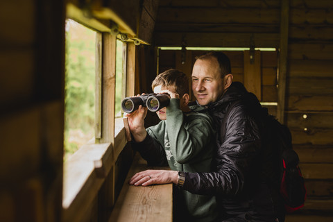 Boy and father birdwatching with binoculars stock photo