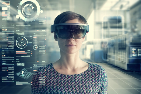 Frau mit Mixed-Reality-Smartglasses vor transparentem Bildschirm, lizenzfreies Stockfoto