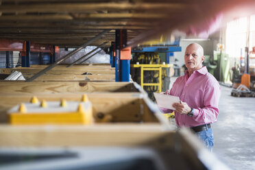 Man with tablet in industrial hall looking at shelves - DIGF02434