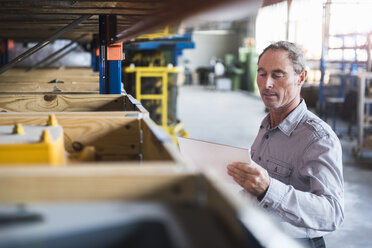 Mann schaut auf Tablet in Industriehalle - DIGF02435