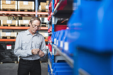 Man in storehouse examining screw - DIGF02437