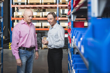 Two men in storehouse examining screw - DIGF02438