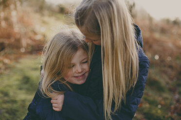 Two cute blond sisters cuddling outdoors - NMSF00083