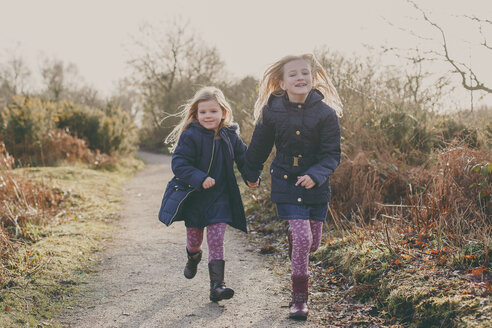 Zwei Schwestern laufen zusammen auf einem ländlichen Weg - NMSF00084