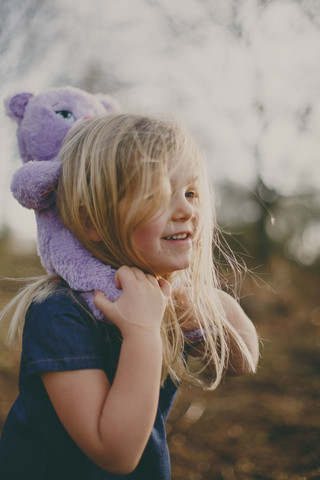 Lächelndes Mädchen trägt einen Teddy im Freien, lizenzfreies Stockfoto