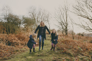 Mother and daughters running on a meadow together - NMSF00092