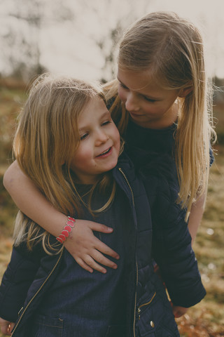Girl hugging her sister outdoors stock photo