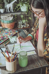 Young woman painting plants with water colors - RTBF00843