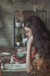 Young woman painting plants with water colors - RTBF00844