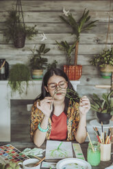 Young woman painting plants with water colors - RTBF00849