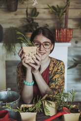 Young woman holding freshly potted cactus - RTBF00880