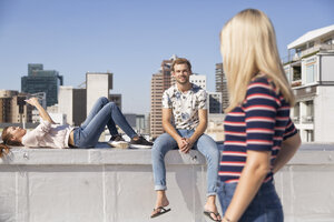Treffen von Freunden auf einer Dachterrasse im Sommer, Frau mit Smartphone - WESTF23083