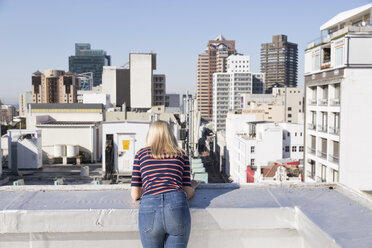 Young woman looking from a rooftop terrace, rear view - WESTF23086