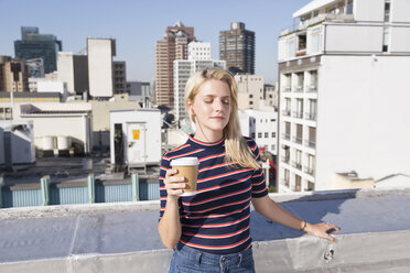 Young woman drinking coffee on a rooftop terrace - WESTF23096