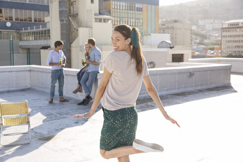 Frau tanzt auf Dachterrasse mit Freunden im Hintergrund - WESTF23105