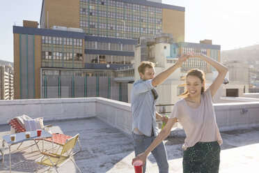 Junges Paar feiert auf einer Dachterrasse und tanzt zusammen - WESTF23108