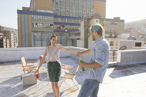 Junges Paar feiert auf einer Dachterrasse und tanzt zusammen, lizenzfreies Stockfoto