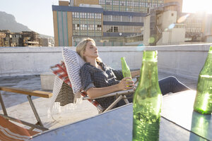 Junge Frau entspannt sich auf ihrer Terrasse - WESTF23125