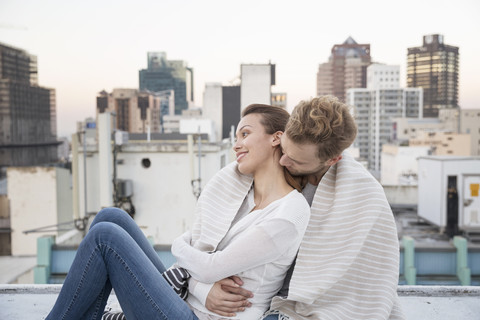 Romantisches Paar sitzt auf der Dachterrasse und genießt die Aussicht, lizenzfreies Stockfoto