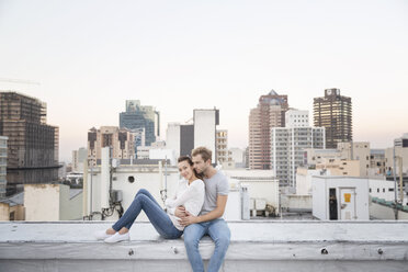 Romantic couple sitting on rooftop terrace, enjoying the view - WESTF23154