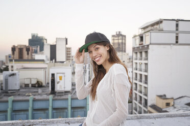 Junge Frau steht auf einer Dachterrasse und lächelt - WESTF23156
