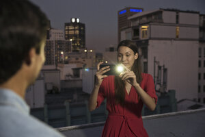 Junge Frau fotografiert ihre Freunde auf einer Dachterrassenparty - WESTF23158
