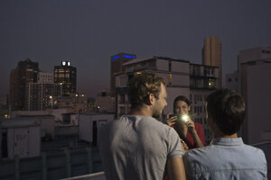 Junge Frau fotografiert ihre Freunde auf einer Dachterrassenparty - WESTF23159