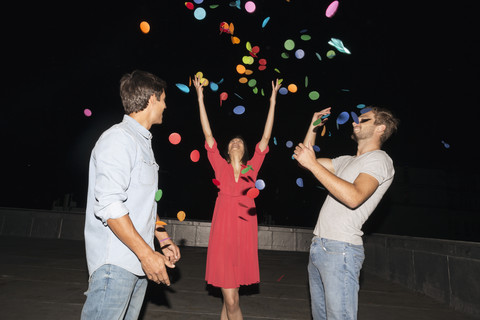 Junge Leute feiern eine Dachterrassenparty und werfen Konfetti, lizenzfreies Stockfoto