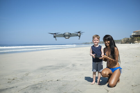 Junge Frau und Junge am Strand fliegen Drohne - ABAF02155