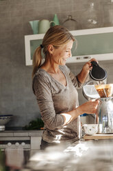 Glückliche Frau zu Hause in der Küche bei der Zubereitung von Kaffee - JOSF00764