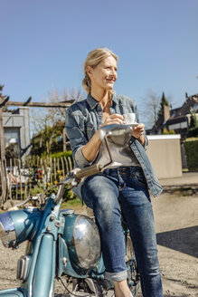 Lächelnde Frau mit Oldtimer-Motorrad in einer Kaffeepause - JOSF00779