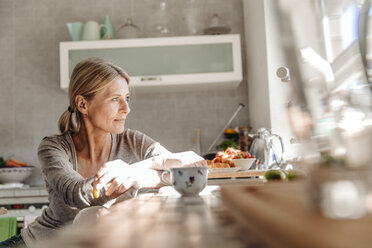 Woman at home in kitchen looking out of window - JOSF00781