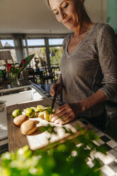 Frau in Küche schneidet Limetten und Kiwis - JOSF00802