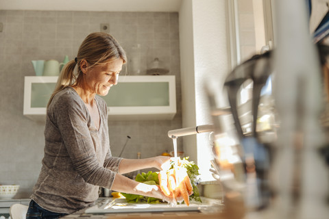 Woman in kitchen washing carrots stock photo