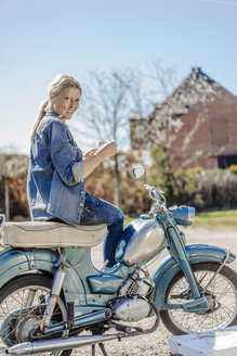 Lächelnde Frau auf altem Motorrad bei einer Kaffeepause - JOSF00812