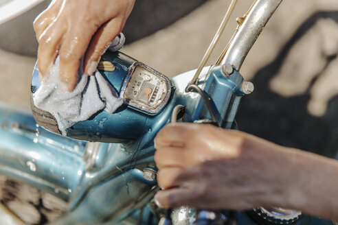Nahaufnahme einer Frau beim Reinigen eines alten Motorrads - JOSF00826