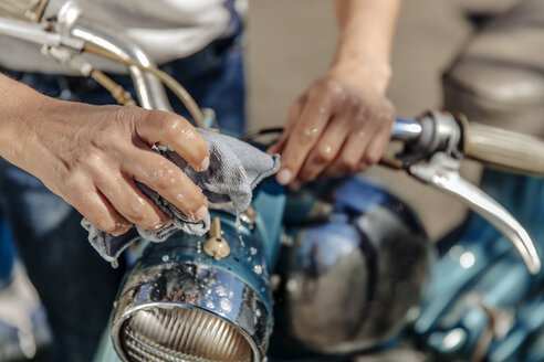 Nahaufnahme einer Frau beim Reinigen eines alten Motorrads - JOSF00828